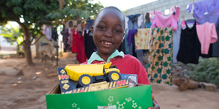 Boy in Zembia holding shoebox gift with yellow truck