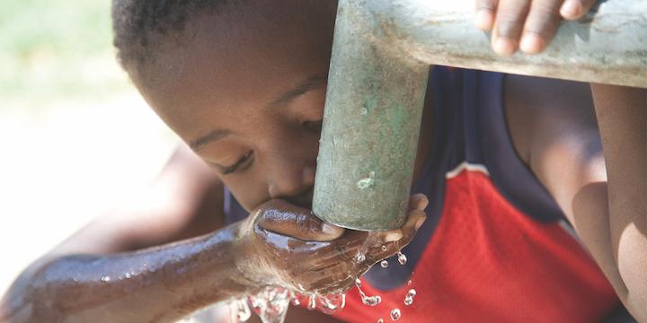 Boy drinking from water pump