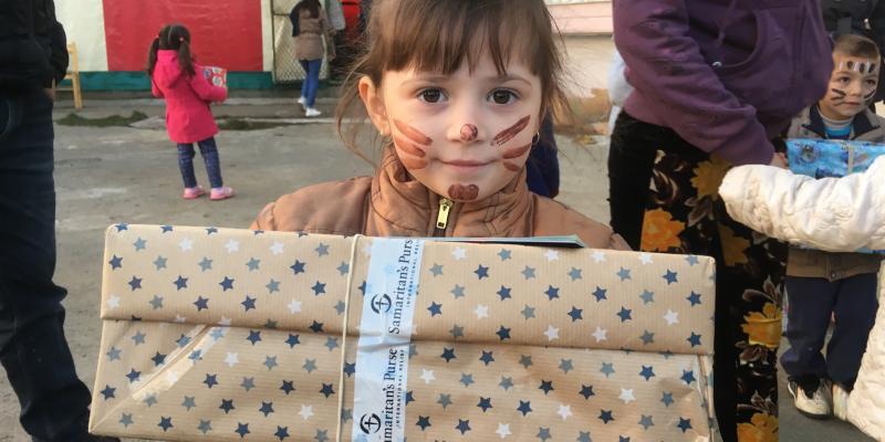 Girl with cat face paint holding a shoebox