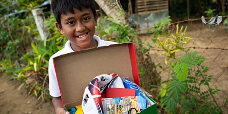 young boy shows open shoebox with football inside