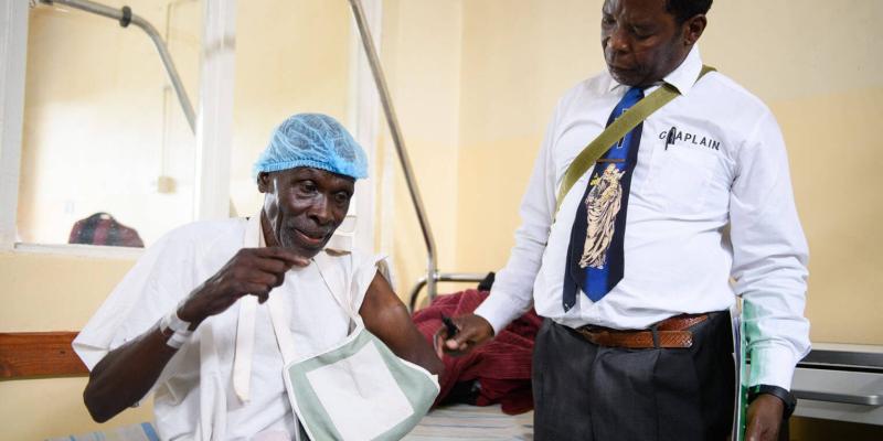 Gamaliel stands bedside with Jephither, one of 44 Malawians to receive surgery from Samaritan's Purse doctors, before he enters the operating room.