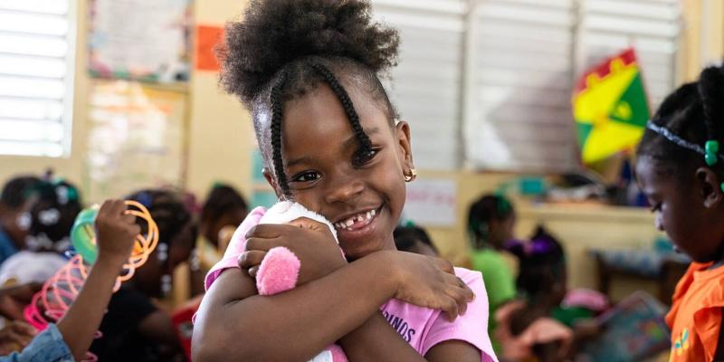 A girl in Carriacou joyfully snuggles up to the “wow” toy she found in her shoebox gift.