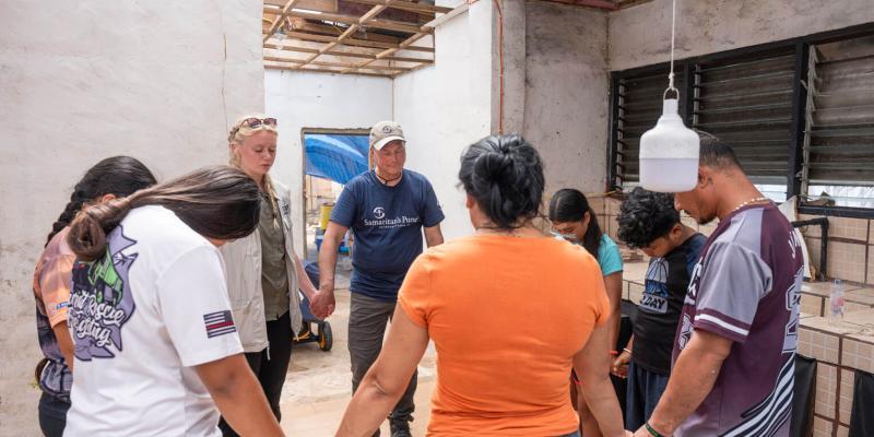 Distribution Coordinator Shawn Kostrzewa (center) prays with the Crisostomo family when Samaritan’s Purse delivered relief items to their storm-battered home on top of a mountain.