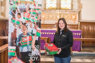 Project leader holding a shoebox by a banner