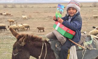 boy on a donkey holding shoebox