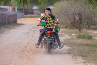 Happy child on motorbike with shoebox in hand