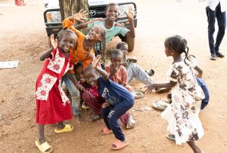 Children smiling as they gather around cooked meals