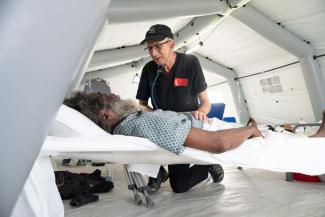 Dr. Joe Lamb, a longtime DART physician with Samaritan’s Purse, encourages an elderly patient brought in the first day of operation at the field hospital.