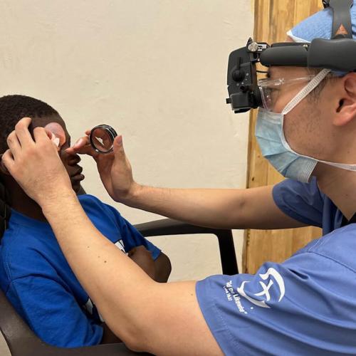 A medical team member examines a young patient’s eyes prior to surgery.