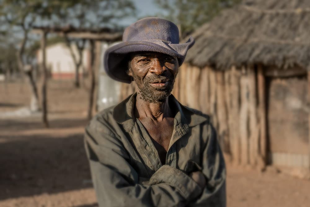 Man in Himba village standing in front of a mud hut